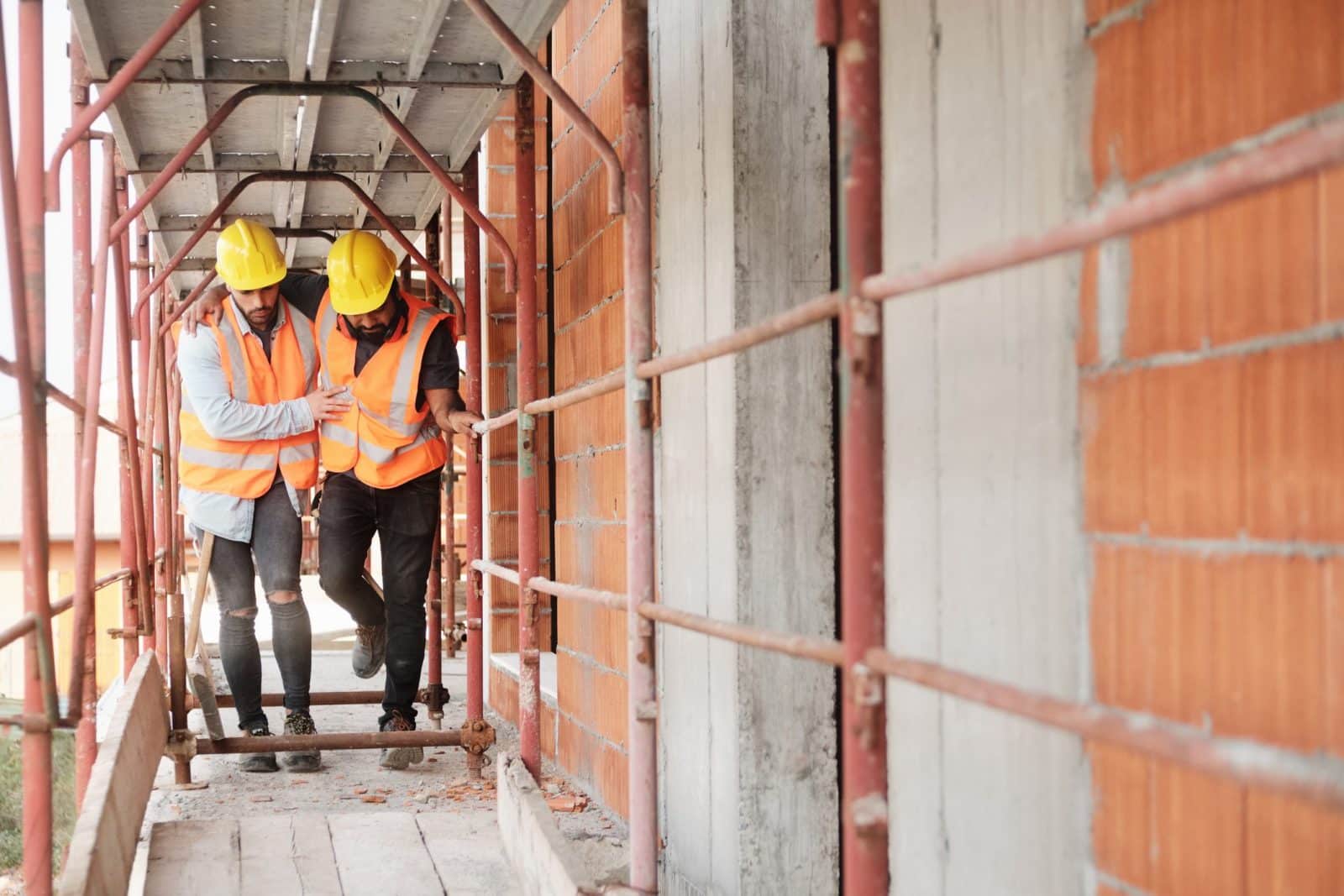 A construction worker helping his injured coworker.