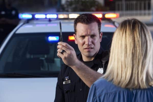 Police officer conducting a field sobriety test on a drunk driver at night.