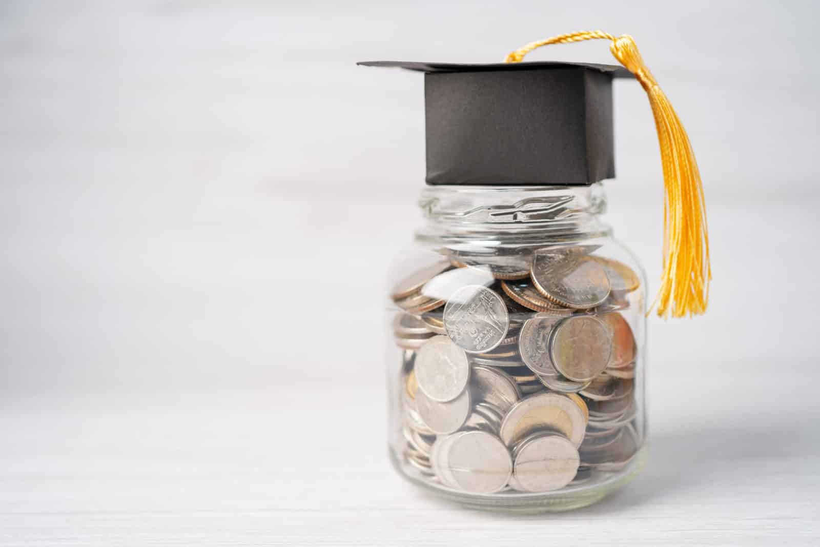 A graduation cap sitting on a jar of quarters.