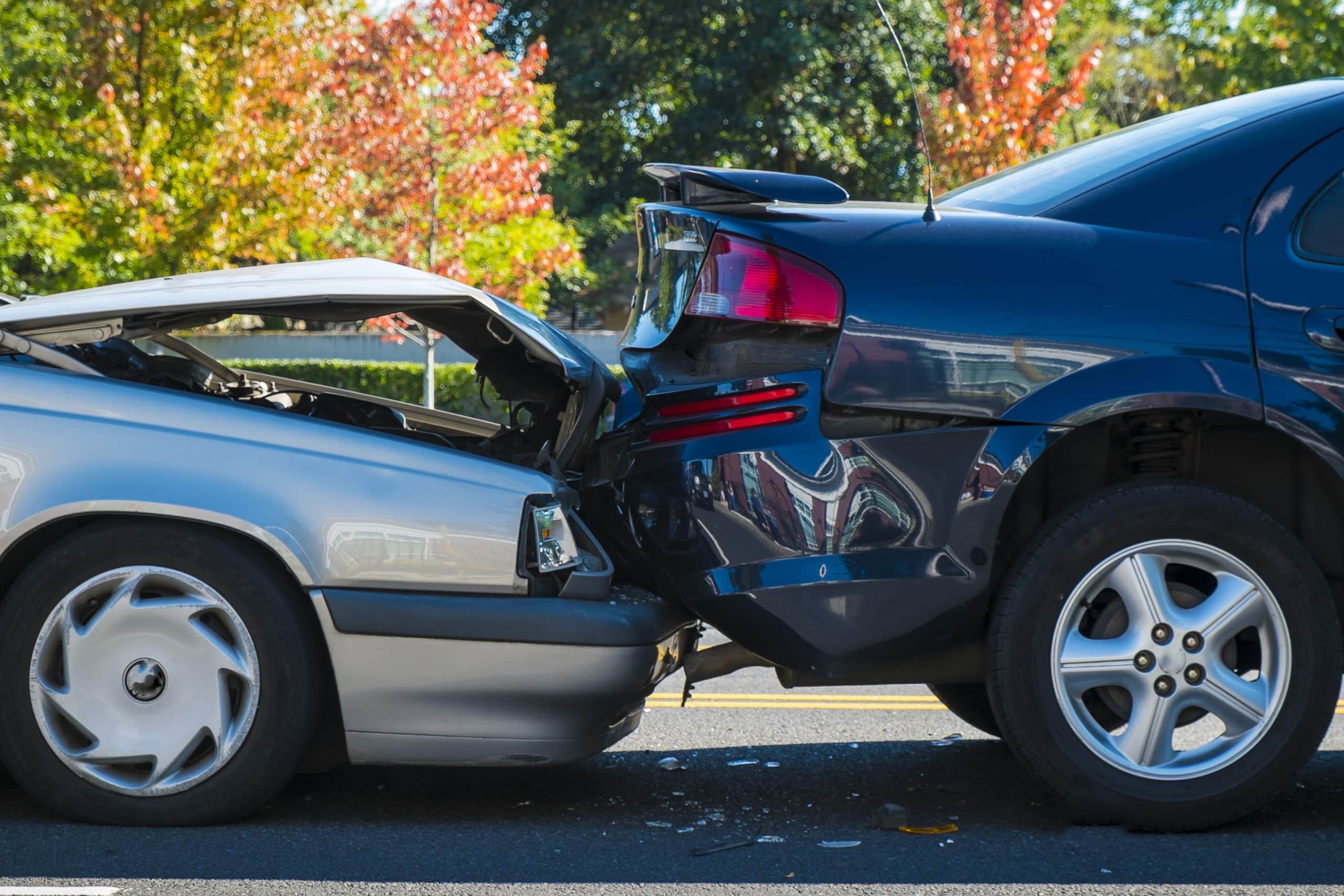 A rear-end car accident involving 2 vehicles on a city street, showing significant damage to both cars.