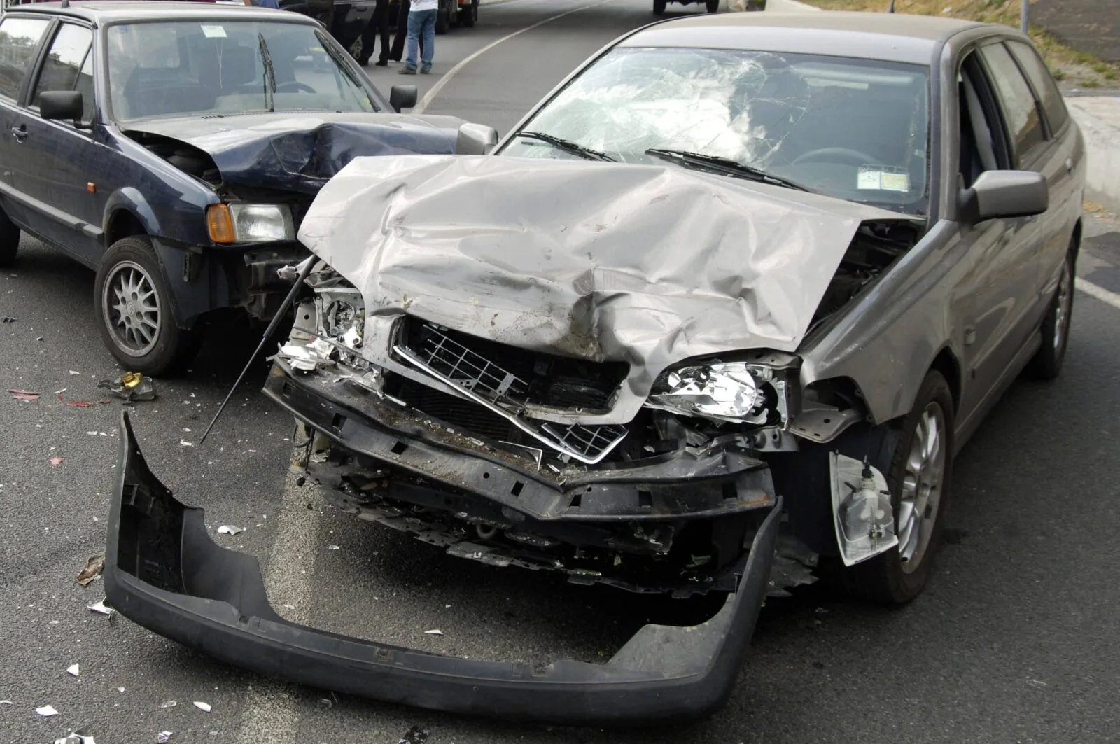 Two heavily damaged cars on a roadway after a front-end collision, with debris scattered around the scene.