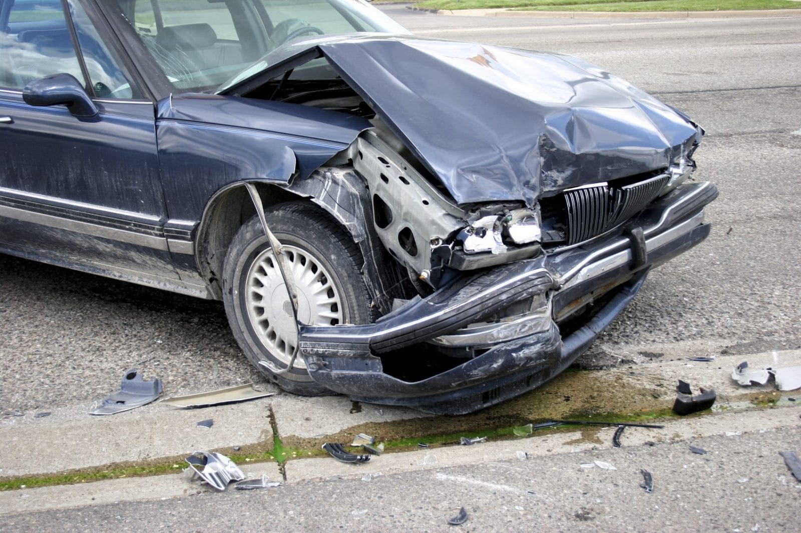 Front view of a heavily damaged car with a crumpled hood and bumper after an accident on the street.