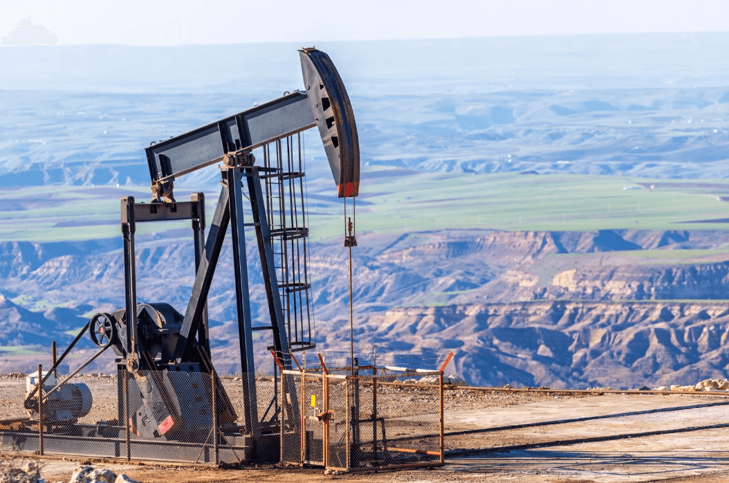 An oil pumpjack in a Midland oilfield, set against a backdrop of expansive hills and valleys.