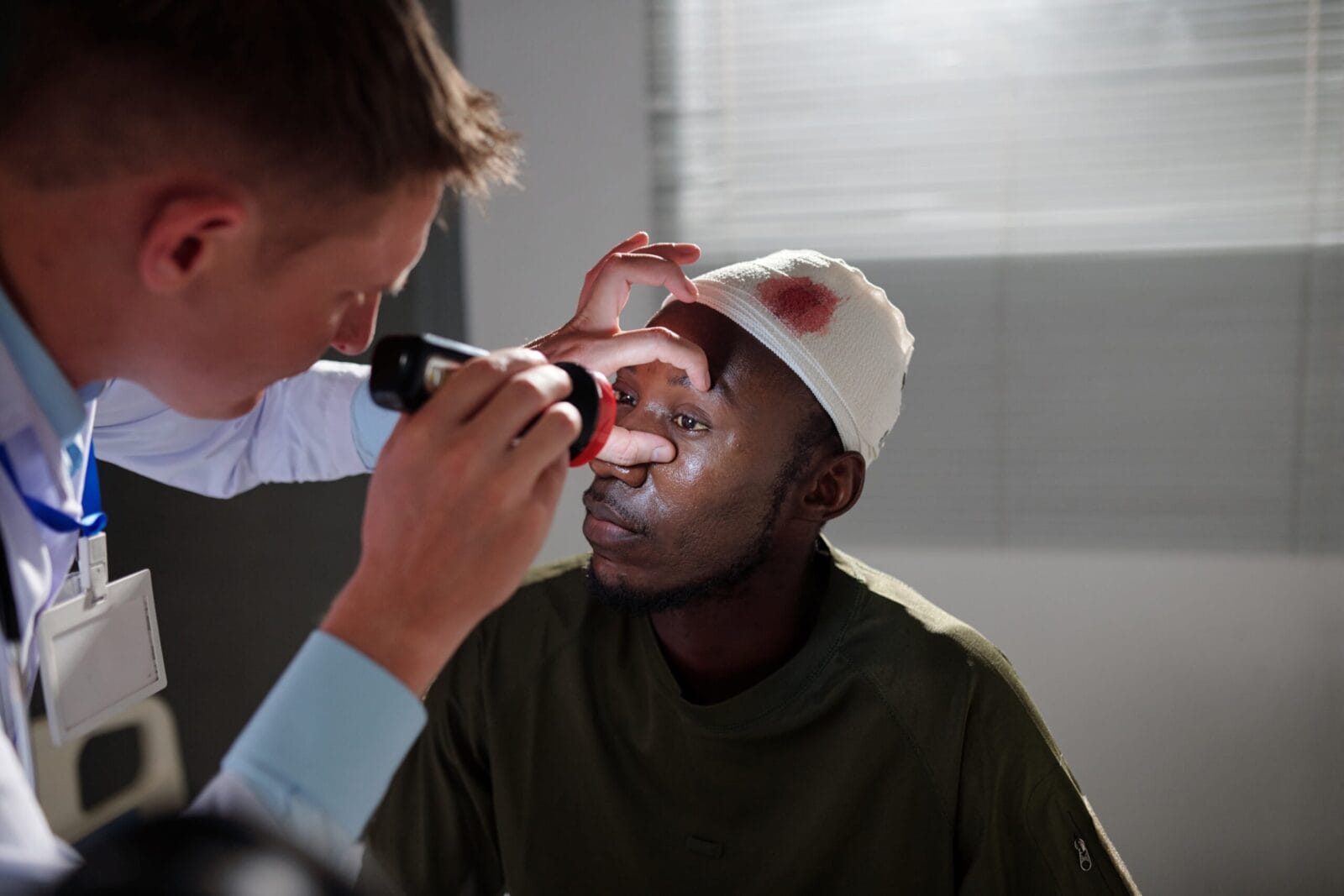 Military man with brain injury looking at beam of light when doctor checking reaction on his pupils